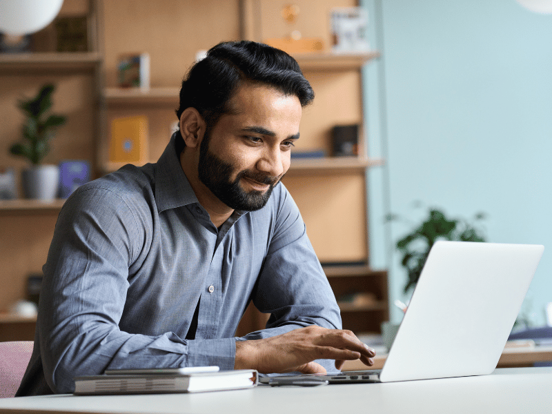 A male property manager looks at resumes from a recent job posting on a laptop. 