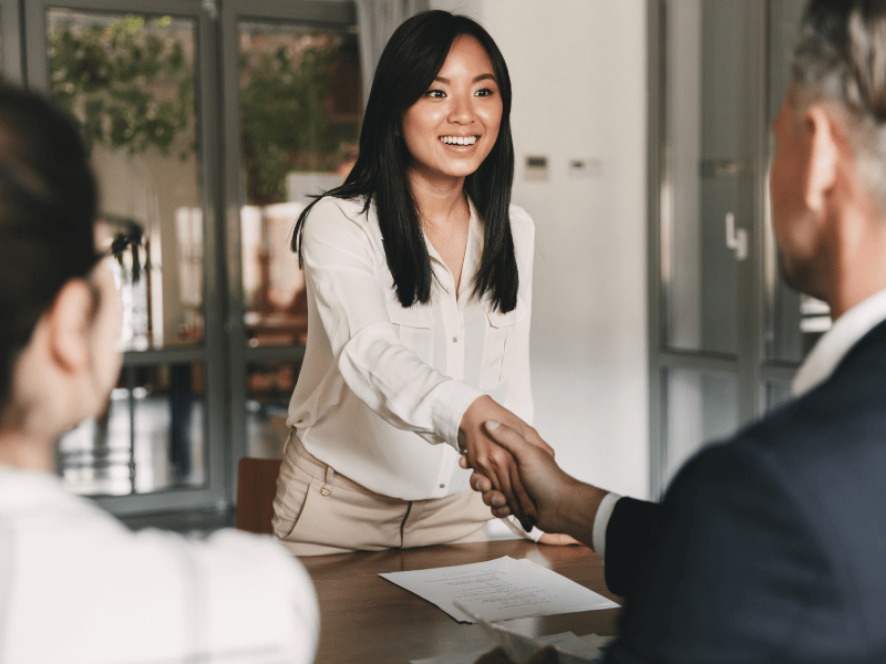 A female candidate shakes hands with managers of a property management company. 